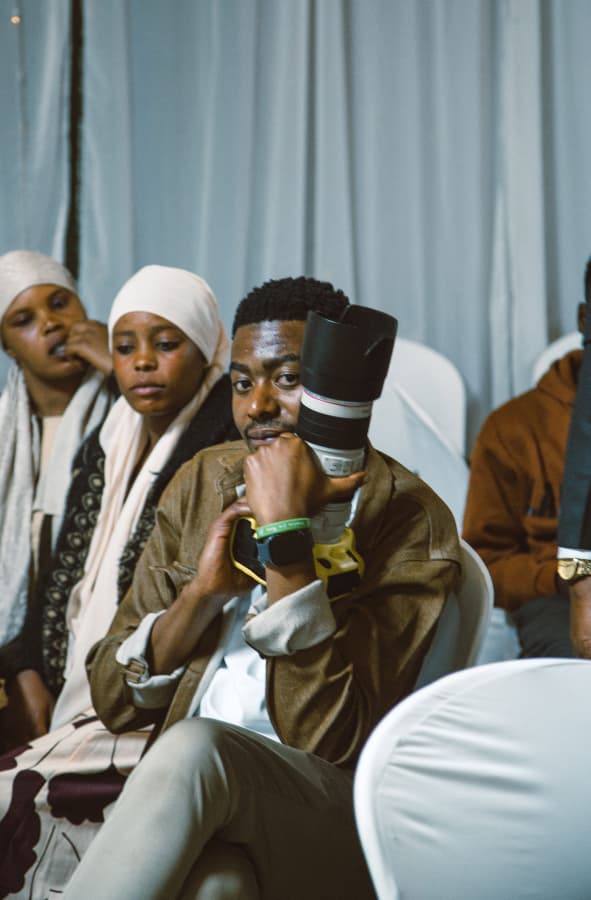 Prosper Chando seated with a camera at a community event